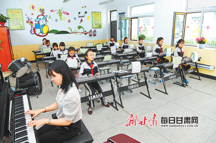 古浪县富民完全小学音乐教室内同学们弹琴唱歌