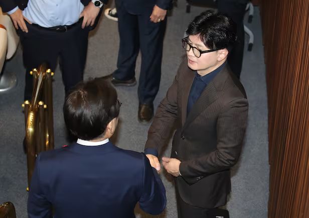 当地时间2024年12月4日，李在明和韩东勋握手交谈 