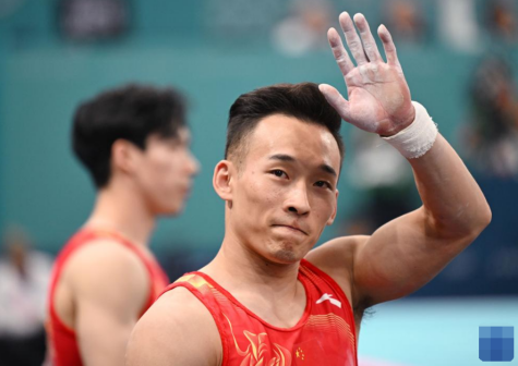 中国选手肖若腾（右）在单杠比赛后